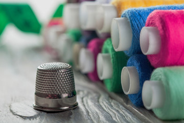 colored sewing thread and bobbin on a wooden background