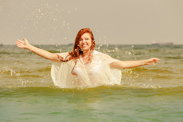 Redhead woman playing in water during summertime