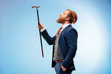 The barded man in a suit holding cane.