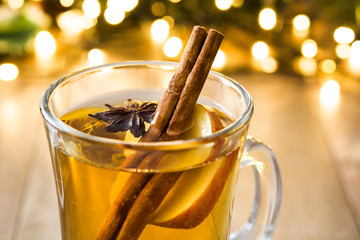 mulled cider in glass, ornaments and christmas light on wooden table
