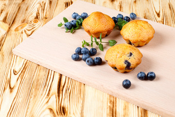 Blueberry muffin. Homemade baked cupcake with blueberries, fresh berries, mint on wooden background. Empty space for text.