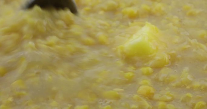 Close video of stirring a tablespoon of margarine into cream style corn with a spoon while heating.