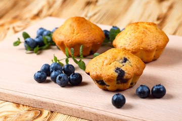 Blueberry muffin. Homemade baked cupcake with blueberries, fresh berries, mint on wooden background. Empty space for text.