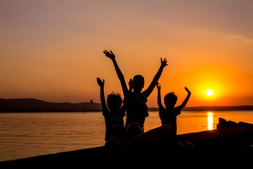 Silhouettes of mother and kids at sunset