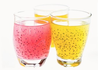 Two yellow and one pink fruit drinks with basil seed in glasses, isolated on white.