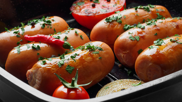 Fried sausages with herbs and vegetables in grill pan