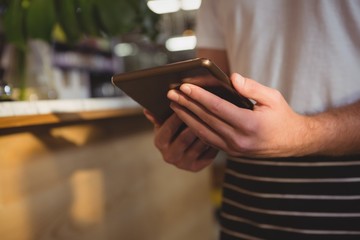 Midsection of waiter using digital tablet