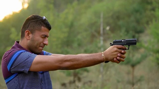 Young arab man is shooting from a gun, close up