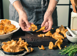 A woman searches for fresh chanterelles on the boards in the kitchen. Fresh chanterelle mushrooms.