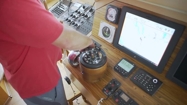Man navigating a boat, hand on navigation gear.