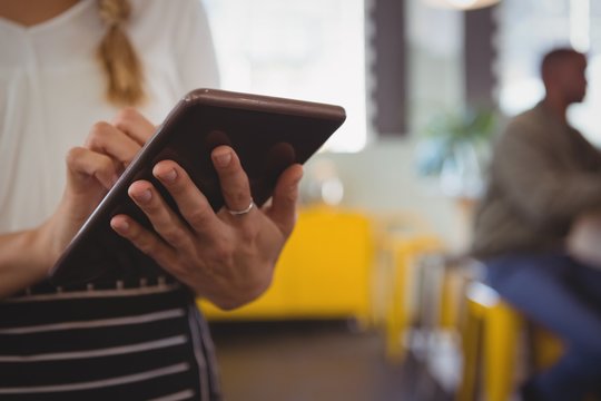 Mid section of waitress using tablet