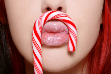 Close-up shot of beautiful woman lips with sparkly gloss and lollipop