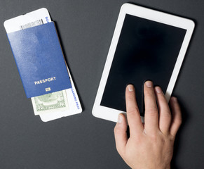 Business air travel, mobility and communication concept: tablet pc or buying airliner tickets online. Passports with boarding pass and 2 dollars 
