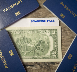 4 passports, 2 dollars and boarding pass on wood background, family travel concept