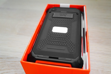 New black-orange rugged smartphone in box, back cover view