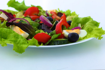 salad from fresh vegetables in a plate on a table, selective focus