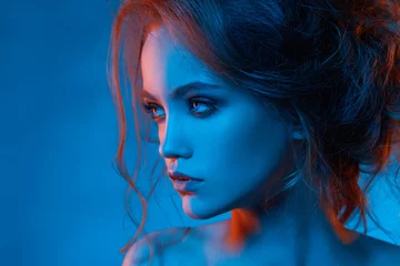 Fotobehang Portret van mooi meisje in blauw licht en rood licht close-up met kapsel © borysenko