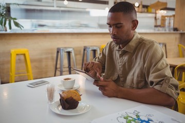 Young man using digital tablet at cafe