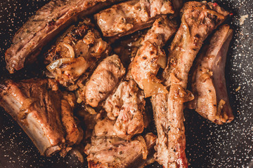 Roasted pork ribs with onion in frying pan, top view