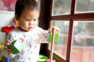 Toddler girl, baby girl paly with wooden toy, serious mode 1.7 years old