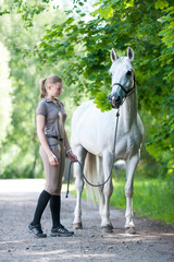 Pretty young blondy teenage girl with her favorite white horse.
