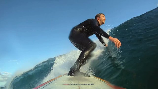 Close up, man surfs large wave