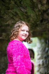 Young little girl portrait looking and smiling at the camera while exploring in an old castle