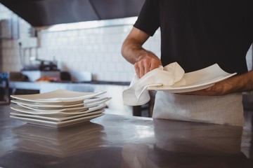 Mid section of waiter cleaning plate in cafe
