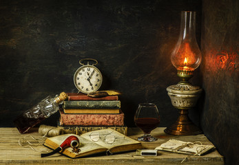 Classic still life with vintage books placed with old lamp,clock,letters and bottle of fresh drink on rustic wooden background © dinasaeed