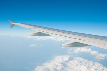The wing of an airplane in the sky above the clouds.