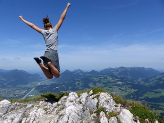 Ein junges Mädchen, welches gerade einen Berggipfel erklommen hat, macht einen begeisterten...