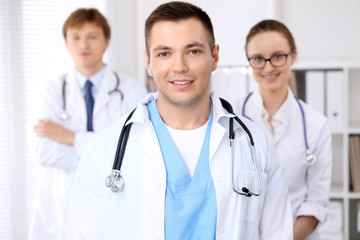 Fototapeta premium Cheerful smiling male doctor with medical staff at the hospital