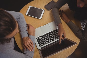 Woman with friend pointing at laptop