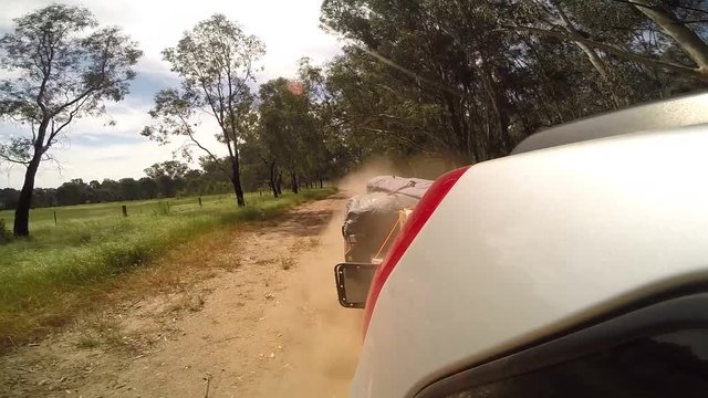Time-lapse, car pulls trailer on dirt road
