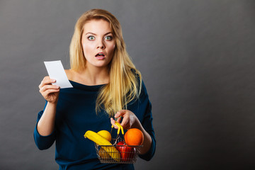 Shocked woman holding shopping basket with fruits