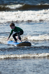 Young little boy on beach taking surfing lessons