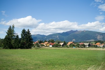 Town, green meadow and hills during sunny and cloudy afternoon. Slovakia