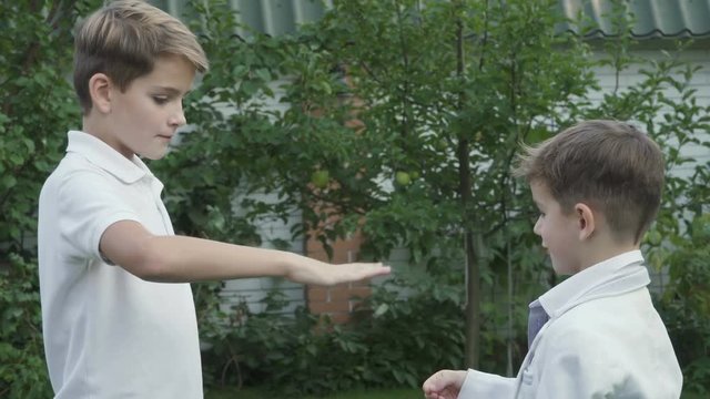 Little boys plays in rock-paper-scissors game outdoors