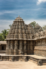 Mysore, India - October 27, 2013: One third of the beige stone central sanctuary, called Trikuta, of Chennakesava Temple in Somanathpur under blue sky. Fully decorated with statues and friezes.