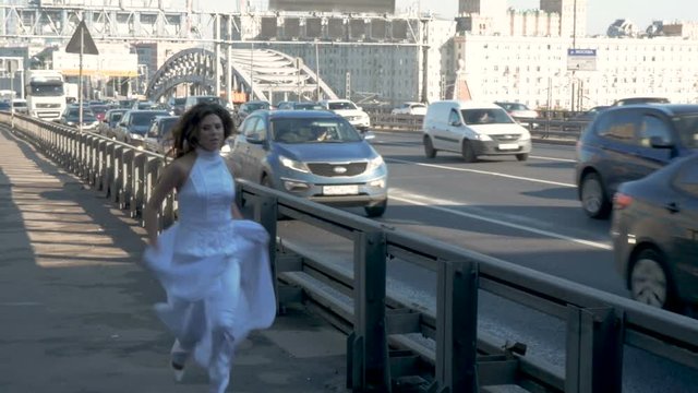 A young woman in beautiful clothes runs along the road. Slow motion.