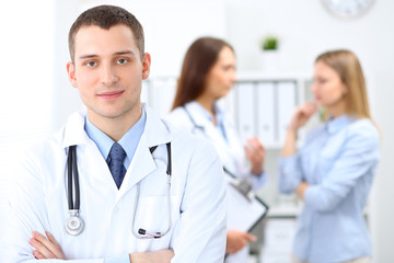 Fototapeta premium Friendly male doctor on the background with patient and physician
