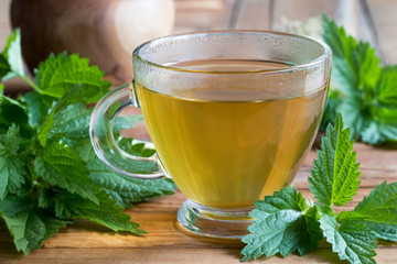 A cup of nettle tea on a wooden background