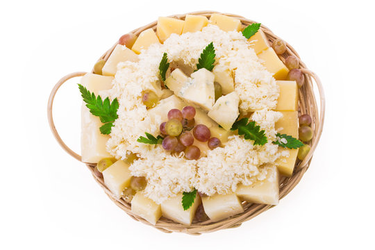 Set of cheeses with grapes in a round basket on a white background. Isolated.