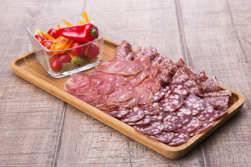 Set of meat delicatessen, tomatoes and peppers on a wooden table.