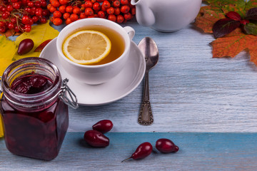 tea with lemon and cherry jam in a jar on a rustic wooden table pines leaves