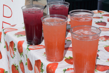 Glasses of blueberry and strawberry beverages with ice at lemonade stand at farmer's market