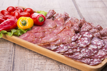 Set of meat delicatessen, tomatoes and peppers on a wooden table.
