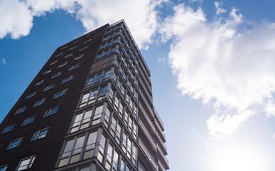 Fototapeta premium a high skyscraper in sunlight with white clouds and a blue sky as background