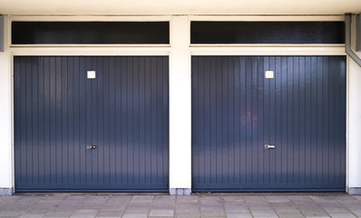 two closed dark gray car garage doors with white pillars in between