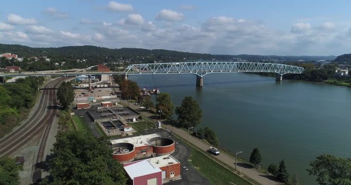 A high angle forward moving aerial establishing shot of the small Western Pennsylvania town of Rochester. The Ohio River is in the distance.  	